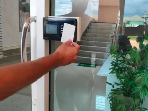 Person using an RFID card on a glass door access reader.