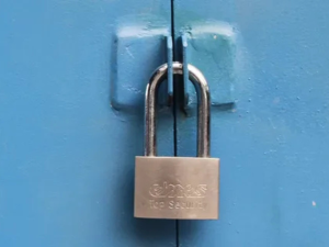 Brass padlock securing a metal bolt on a blue wooden door.