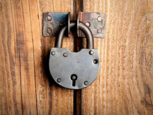 A teal padlock on a wooden door with locksmith service text overlays.